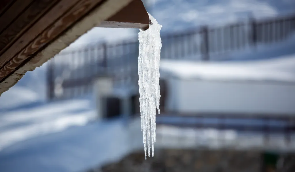 An icy stalactite comes out of a gutter