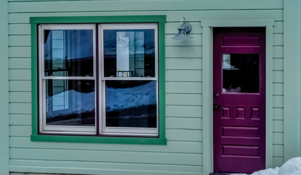 Glass paned purple front door and single hung windows 