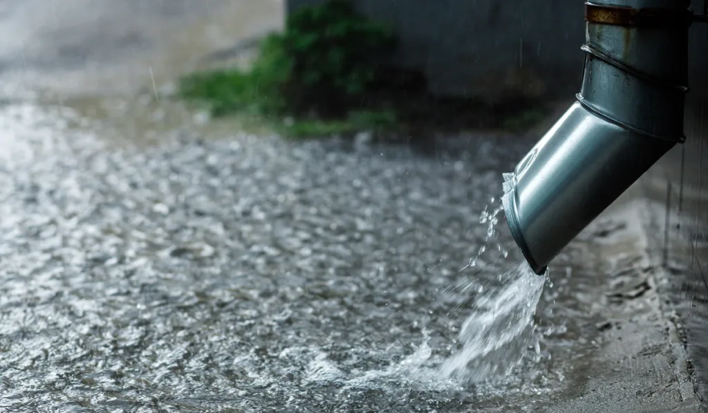 Rain water flowing from metal downspout during a flood