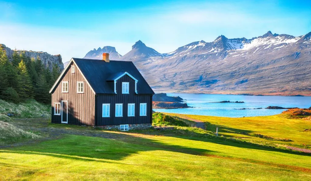 big old farm house on a valley with mountains on the background