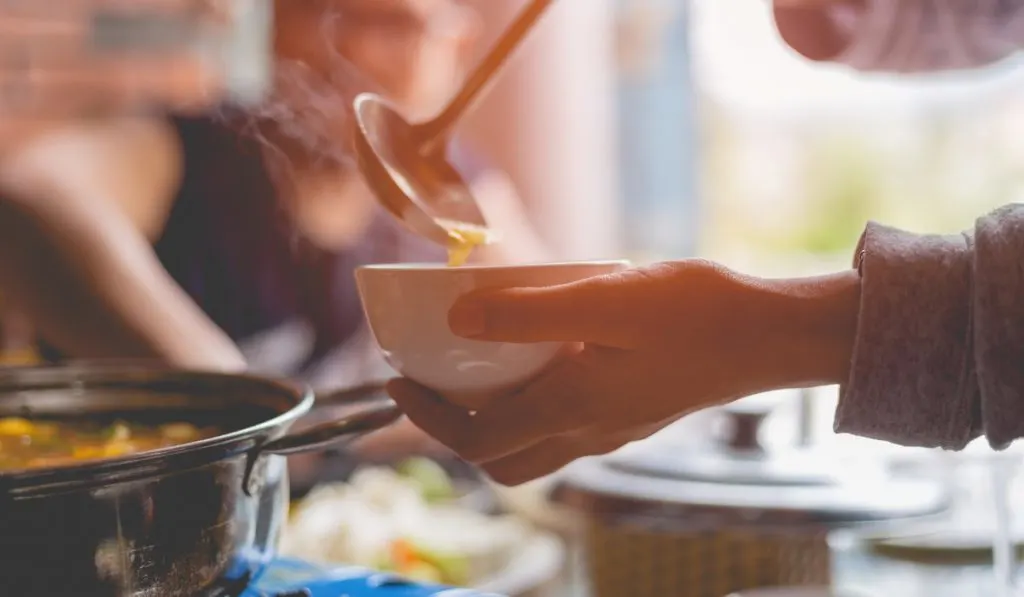 woman holding ladle hand pouring hot soup for dinner 