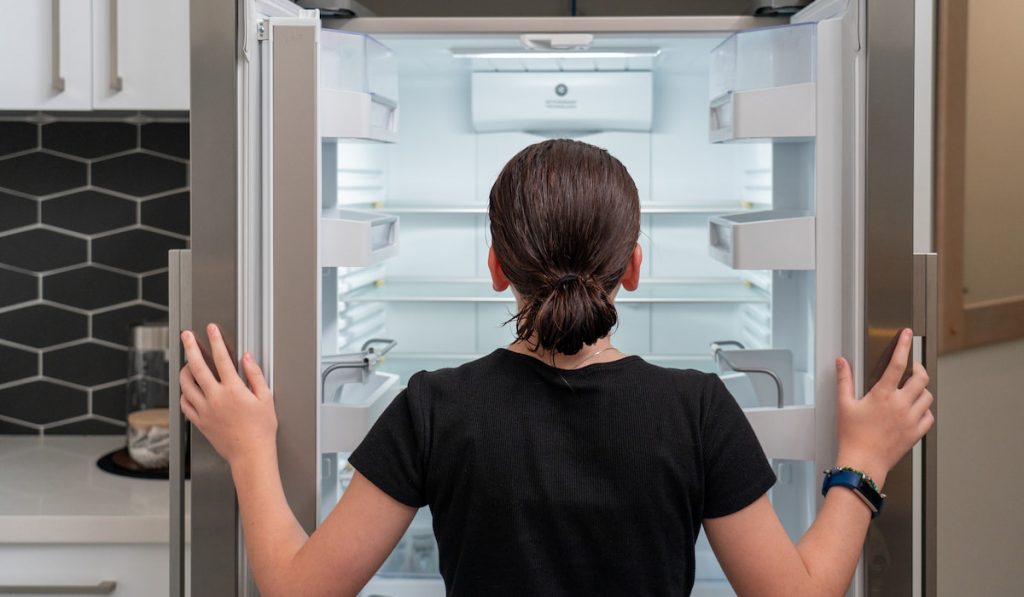 young girl looking into an empty Refrigerator fridge