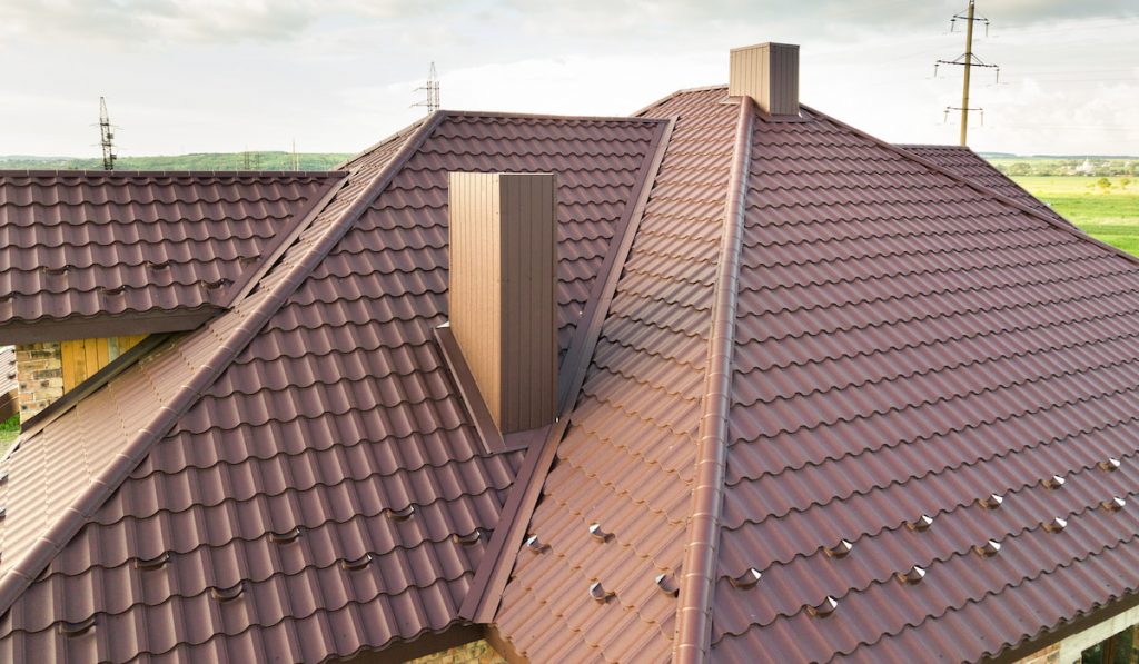 Detail view of house rooftop covered with brown metal tile sheets
