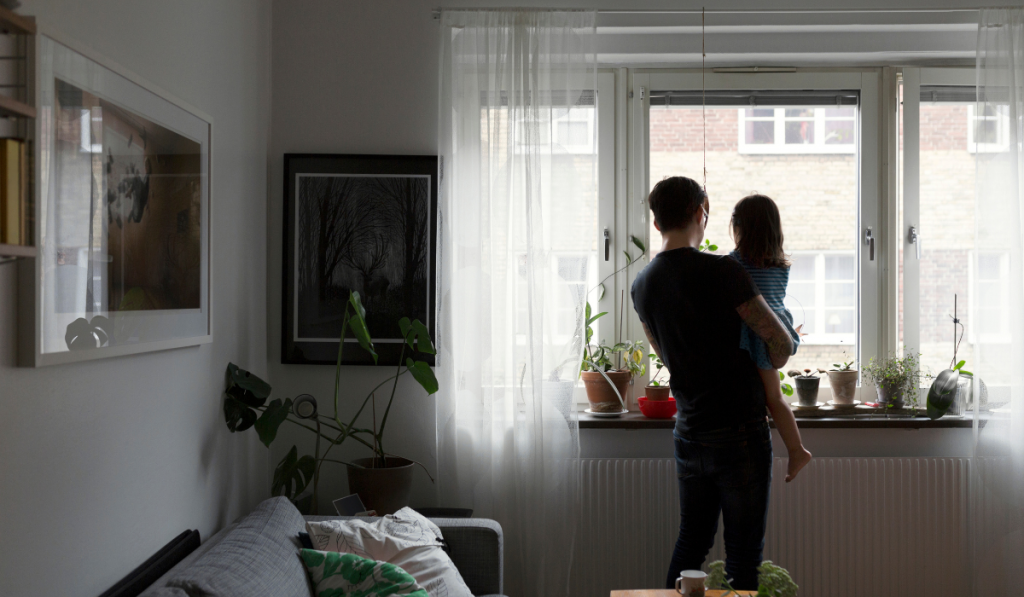 Father holding daughter by window

