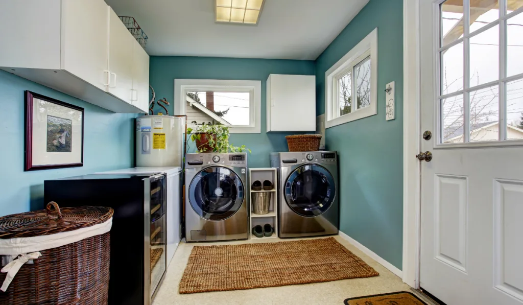 Light blue laundry room with modern steel appliances and white cabinets