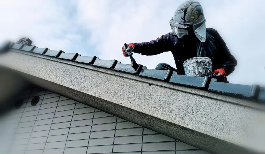 Painter painting roof tiles of a japanese house