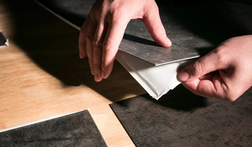 Removing backing from peel and stick vinyl flooring tiles.
