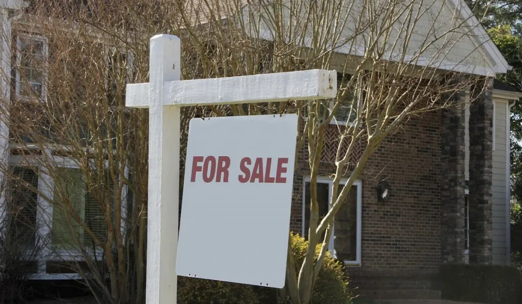 Real estate For Sale sign with  house for sale in background