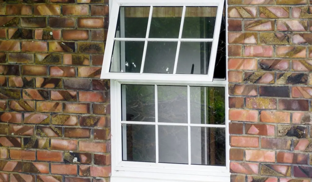 View of white wooden divided grid window on brick wall