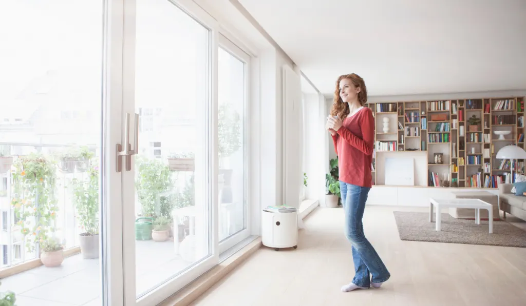 Woman at home looking out of window
