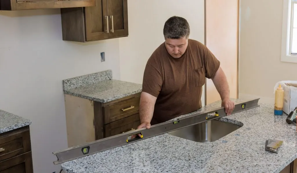 Worker hanging level on the countertop of kitchen for renovation