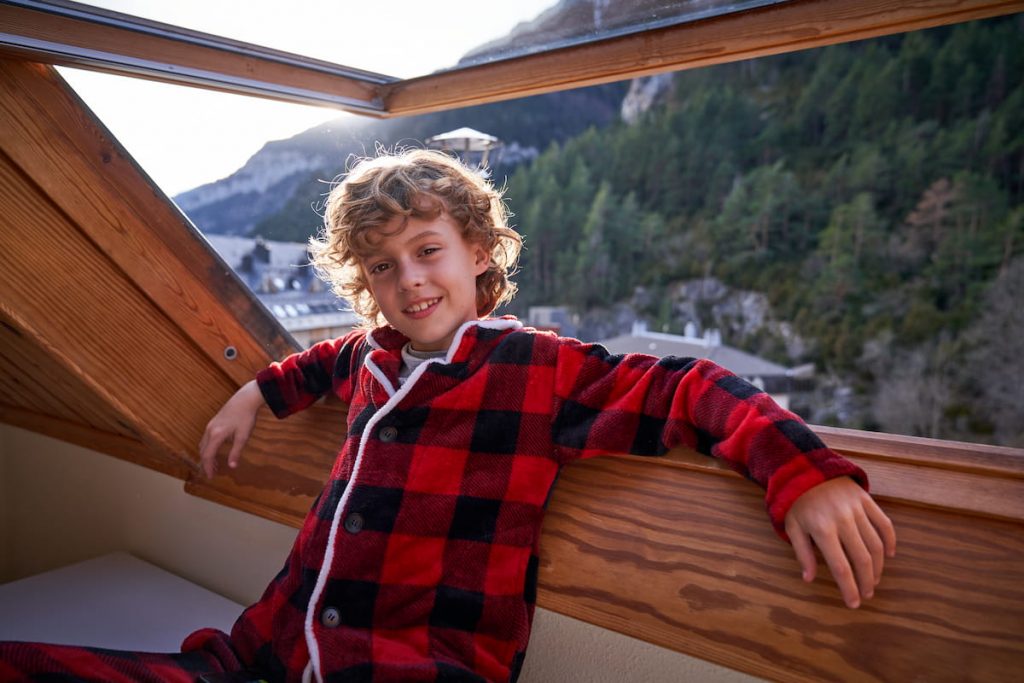 a boy near wooden impact window with mountains view