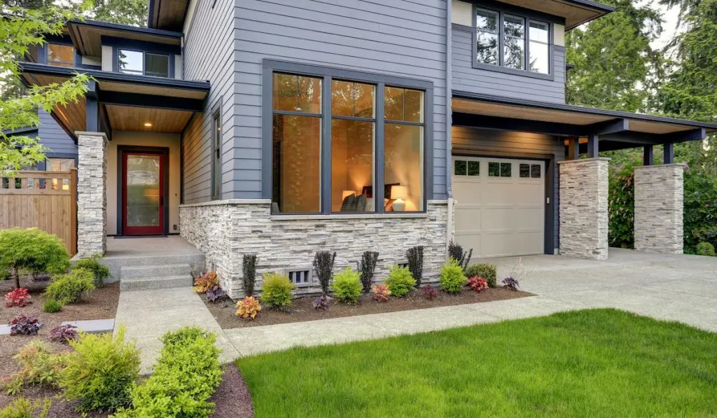 grey two-story exterior in Bellevue with large impact windows,  stone foundation veneer, covered porch and concrete pathway