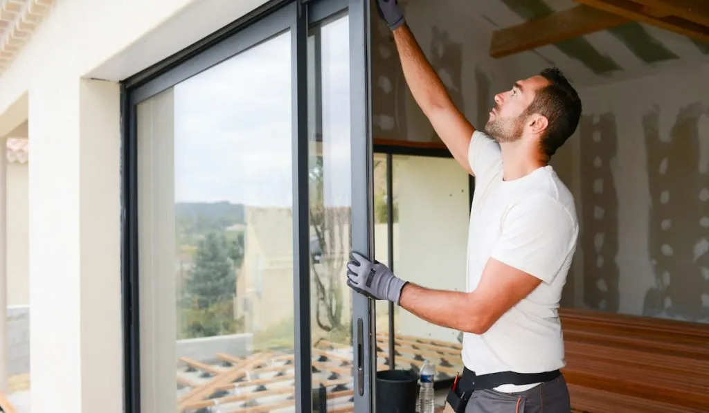 handsome young man installing bay window in a new house construction site
