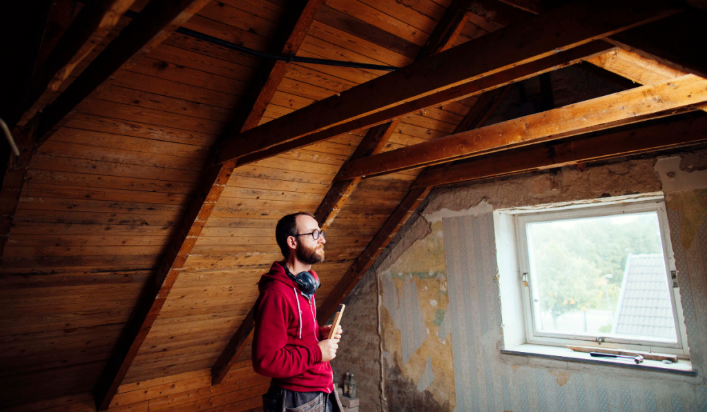 Side view of man inspecting attic under renovation