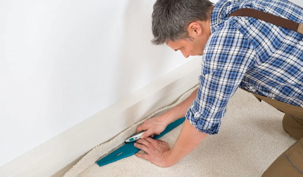 worker fitting new carpet on the floor