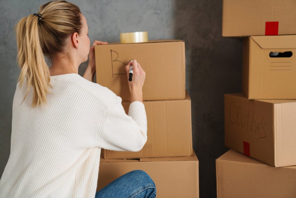 young woman moving out from her old house, naming boxes