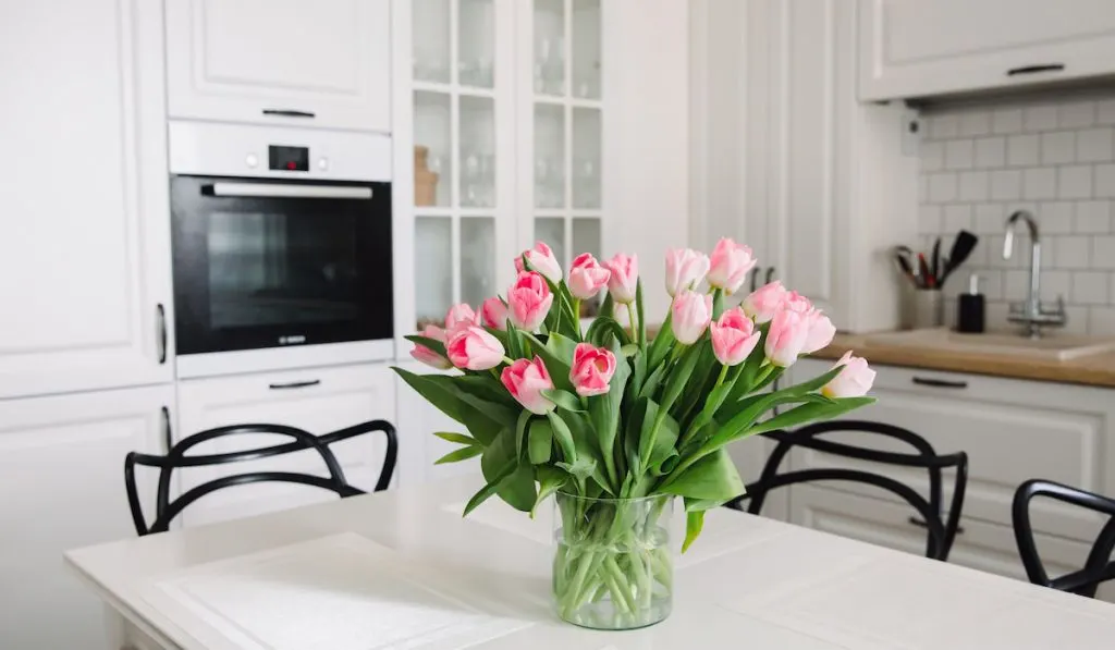 Bouquet of pink tulips in a transparent vase, on kitchen table