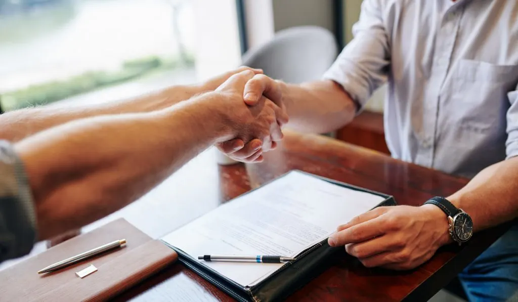 Buyer and seller of a house shakes hand after signing an agreement, negotiation