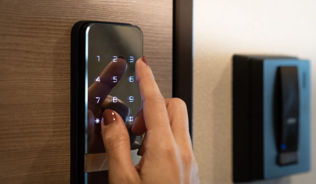 woman pressing number codes on smart lock to control her house lock