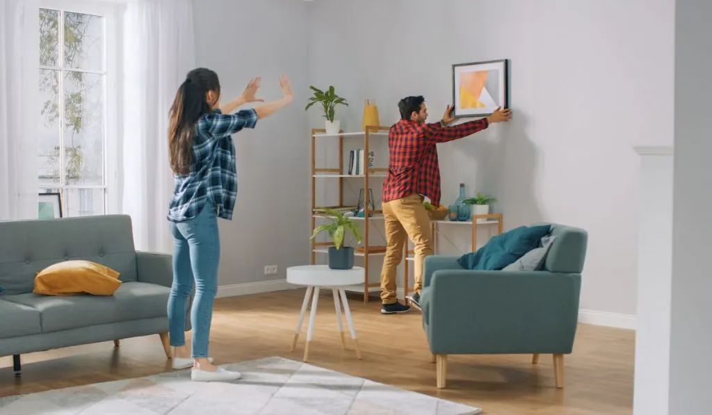 Couple decorating their new home, hanging picture on the wall