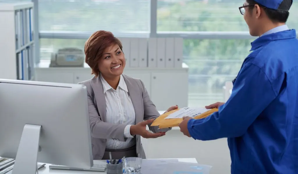Delivery man giving package to a woman in her office