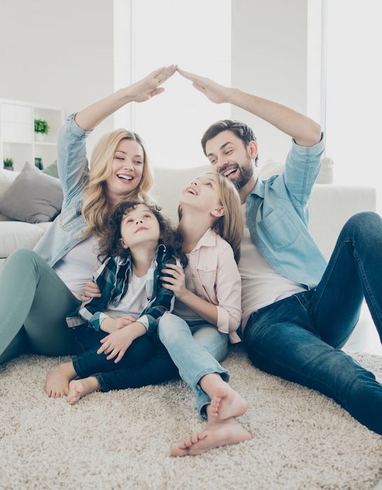 Happy family in their new home making arms roof having fun while sitting on the floor