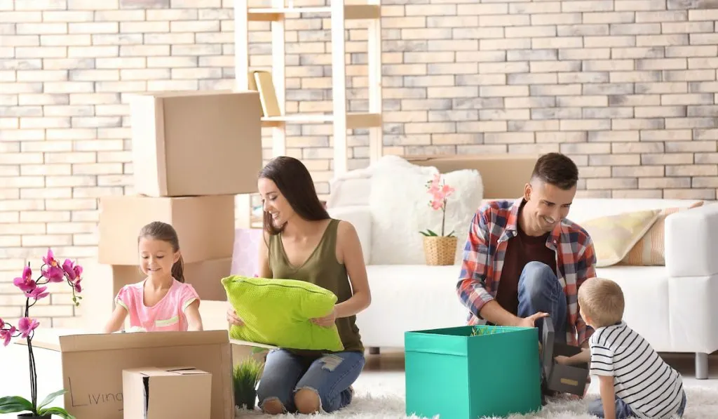 Happy family unpacking cardboard boxes in room at new house
