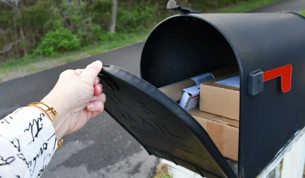 Opening a mailbox full of boxes packages delivered by the mailman USPS