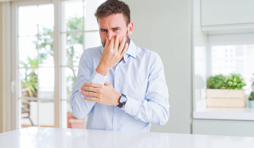 Potential house buyer man smelling something disgusting inside the house