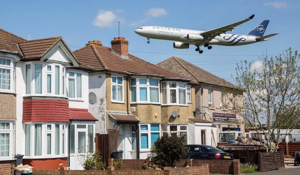 Row of houses near airport, Airplane flies over residential houses as it approaches runway for landing