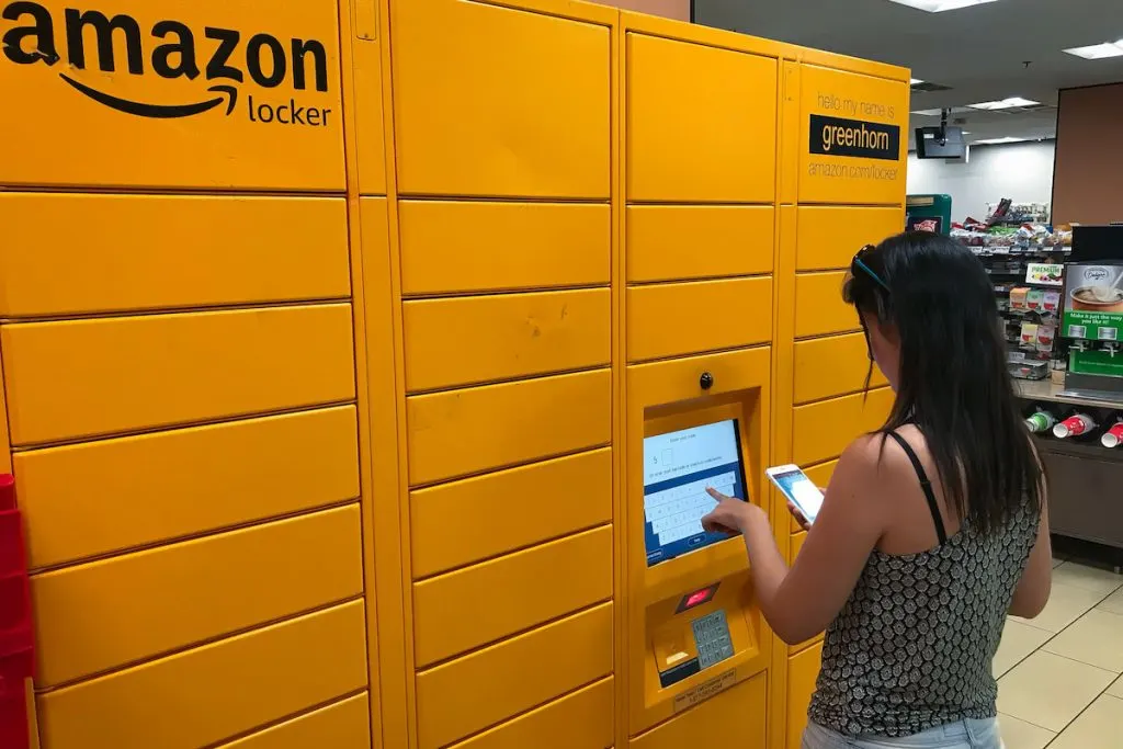 Woman using an Amazon Locker station inside a supermarket to pick up her delivery order