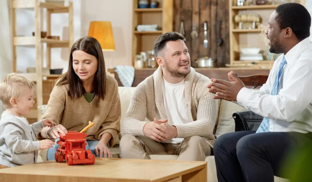 Young family having consultation with a real estate agent at home for selling their house