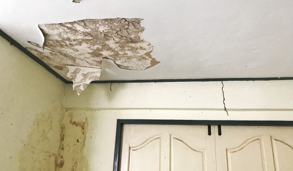 old peeling decay white gypsum board ceiling, wall and door damage by water leaking from raindrop,
