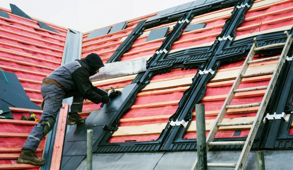 A roofer replacing the tiles on a house roof.