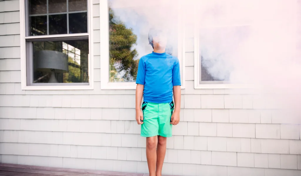 Boy Standing Amidst Smoke Outside House