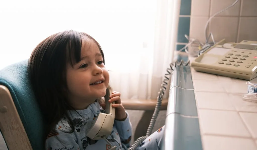 Happy Little Girl που μιλάει σε ένα σταθερό τηλέφωνο