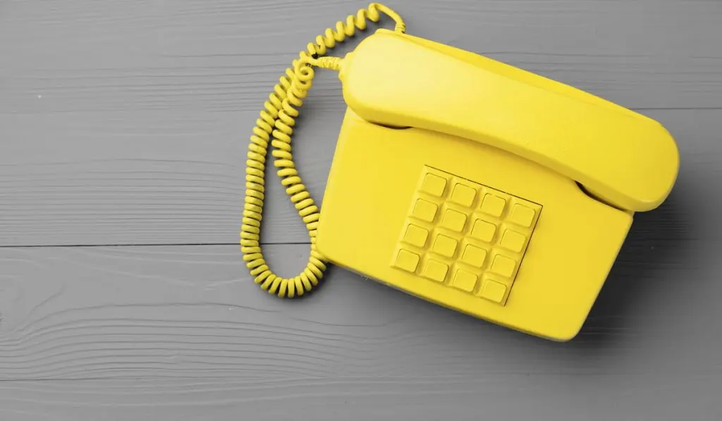 Yellow .landline phone on gray background top view