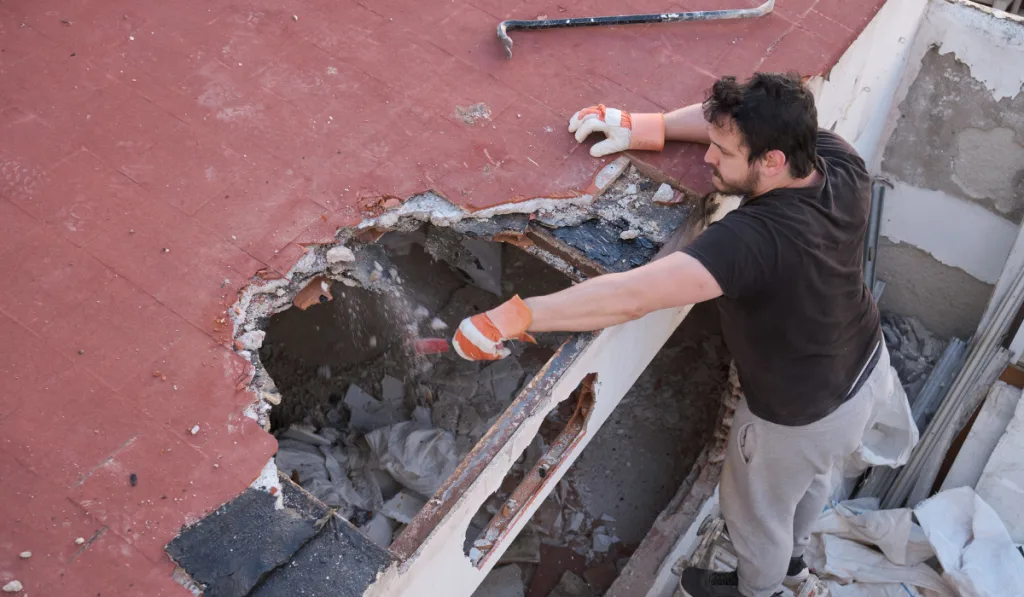 Young man tearing the ceiling of a house down