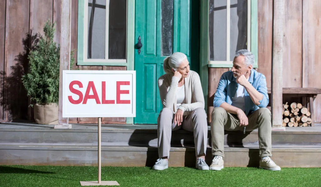 upset senior couple sitting on porch and selling their house