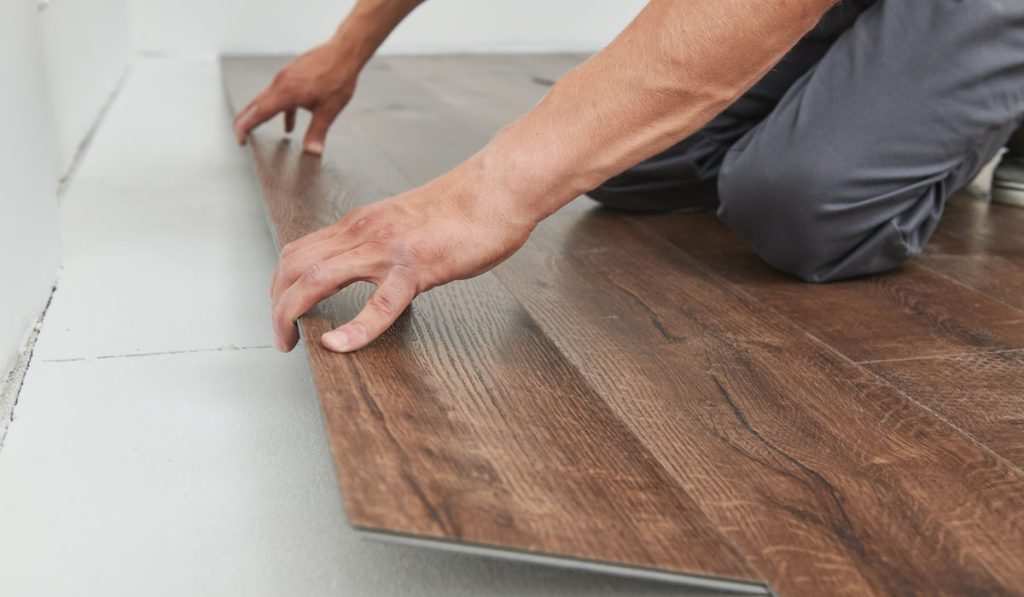 worker installing vinyl plank floor covering at home renovation